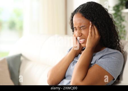 Schwarze Frau, die zu Hause unter Migräne leidet Stockfoto