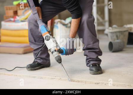 Nahaufnahme eines Bauarbeiters mit einem Bohrhammer auf dem Boden Stockfoto