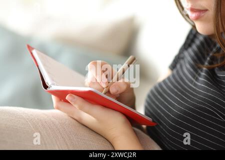 Nahaufnahme Porträt einer Frau, die zu Hause auf einer Couch auf Papier schreibt Stockfoto