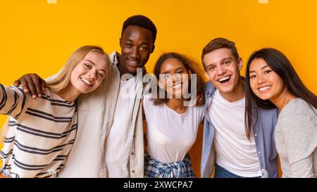 Freundliche internationale Studenten, die Selfie über gelbem Hintergrund machen Stockfoto