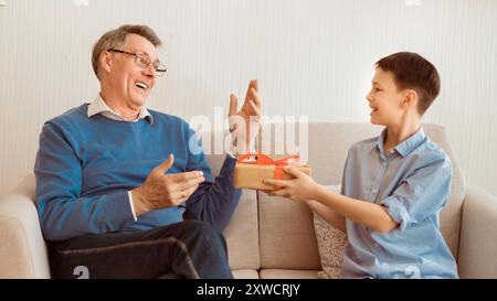 Enkel gratulieren Großvater, verpackte Geschenk Sitzen auf einem Sofa, Panorama Stockfoto