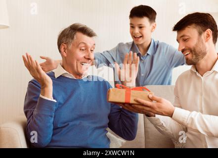 Sohn und Enkel gratulieren älterer Mann saß auf der Couch Indoor Stockfoto
