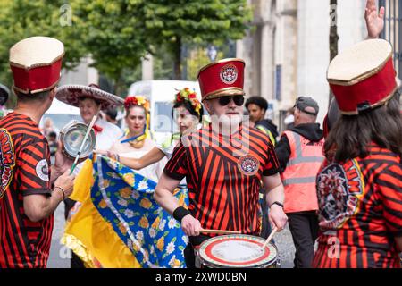 Mitglieder der Beat N Drum Band wärmen sich vor der jährlichen Belfast Mela multikulturellen Karnevalsparade durch das Stadtzentrum auf. Belfast, Großbritannien - 17. August 2024. Stockfoto