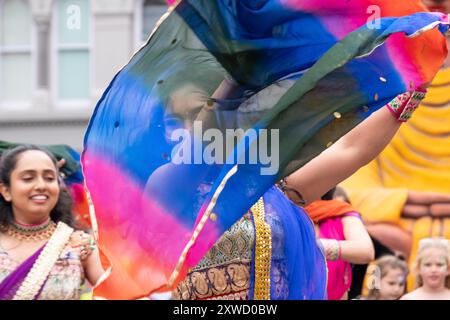 Indische Frau tanzt bei der multikulturellen Karnevalsparade in Belfast Mela, Gesicht teilweise von einem farbenfrohen Schal verdeckt. Belfast, Großbritannien - 17. August 2024. Stockfoto