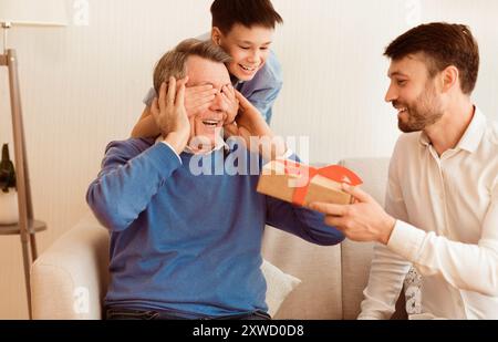 Reifen Sohn und Enkel gratulieren Großvater, Geschenkbox Indoor Stockfoto
