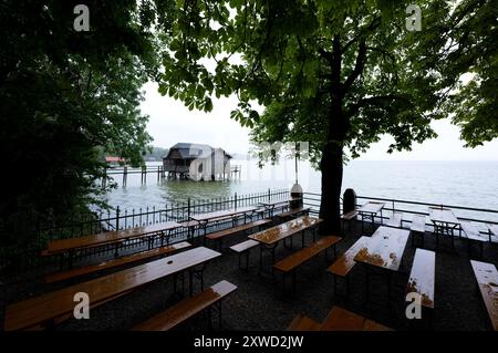 Stegen Am Ammersee, Deutschland. August 2024. Bierbänke und Tische im Regen in einem Biergarten am Ammersee. Im Hintergrund ist ein Bootshaus zu sehen. Quelle: Sven Hoppe/dpa/Alamy Live News Stockfoto