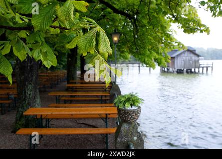 Stegen Am Ammersee, Deutschland. August 2024. Bierbänke und Tische im Regen in einem Biergarten am Ammersee. Im Hintergrund ist ein Bootshaus zu sehen. Quelle: Sven Hoppe/dpa/Alamy Live News Stockfoto