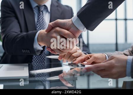 Geschäftsleute oder Anwälte schütteln sich die Hand, wenn sie ein Meeting oder eine Verhandlung in einem sonnigen Büro beenden. Stockfoto