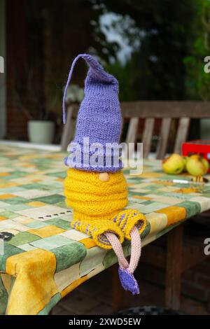 Blaue und gelbe Sommergnome, die auf einem Tisch sitzen. Hausgemachte gestrickte Sommer-Gnome. Stockfoto