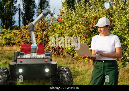 Der Landwirt steuert autonome Roboterroboter mit Roboterarm, der Äpfel auf einem intelligenten Bauernhof erntet. Konzept... Stockfoto