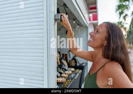 Hispanische Frau in ihren 50ern öffnete ihren Straßenstand, um handgemachten Schmuck aus Aluminiumdraht zu verkaufen Stockfoto