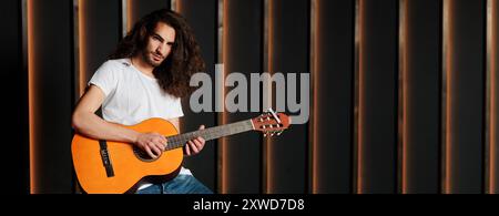 Junger Musiker, der tagsüber Akustikgitarre im modernen Studio spielt Stockfoto