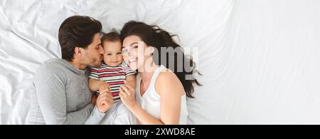 Glückliche Familie, die sich mit ihrem Baby im Bett entspannt Stockfoto