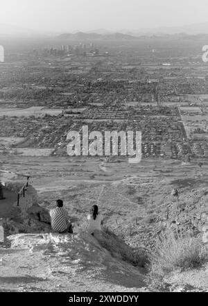 Das junge kaukasische Paar sitzt auf einem Felsen am Dobbins Lookout, South Mountain Park, Phoenix, Arizona, USA. Stockfoto