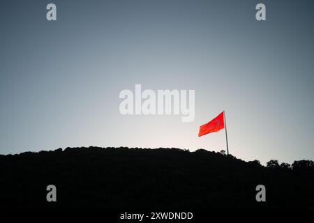 Ein mächtiges Bild der türkischen Flagge, die stolz auf einem Berg winkt und Stärke, Freiheit und Nationalstolz symbolisiert, vor einem Hintergrund von Weite Stockfoto