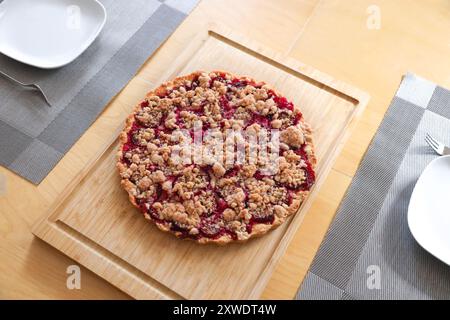 Ein hausgemachter Pflaumenkuchen auf einem Holzbrett mitten auf einem Esstisch. Stockfoto