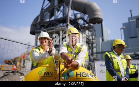 Hamburg, Deutschland. August 2024. Robert Habeck (2. V. l., Allianz 90/die Grünen), Bundesminister für Wirtschaft und Klimaschutz, verschraubt bei seinem Besuch bei der Energie Hub Moorburg GmbH. Gabriele Eggers (links), kaufmännischer Direktor der Gasnetz Hamburg GmbH, symbolisch eine Wasserstoffleitung. Während der Begehung erfuhr Habeck von den Hamburger Wasserstoffprojekten auf dem Gelände des ehemaligen Kohlekraftwerks. Quelle: Marcus Brandt/dpa/Alamy Live News Stockfoto