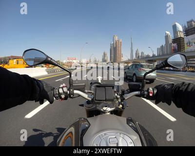 Motorradfahrer auf der Sheikh Zayed Road, Dubai, vorbei an der Skyline der Stadt und an Hochhäusern Stockfoto