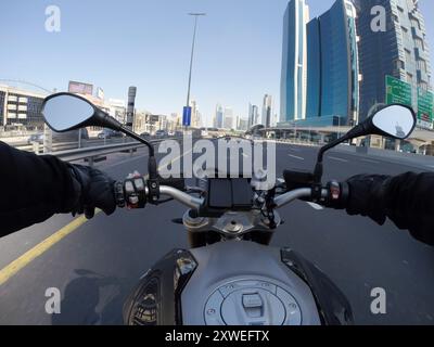 Motorradfahrer auf der Sheikh Zayed Road, Dubai, vorbei an einer Radarkamera zu seiner Linken, umgeben von einer urbanen Skyline und Hochhäusern Stockfoto