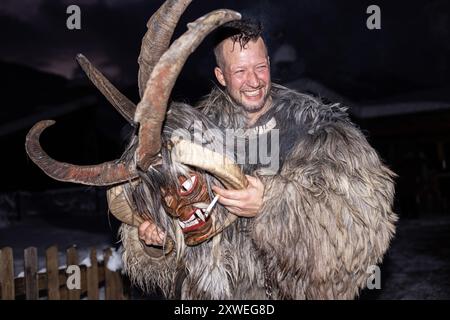 Ein Mann im Pelzkostüm hält die Teufelsmaske während des Nachtfestes Stockfoto