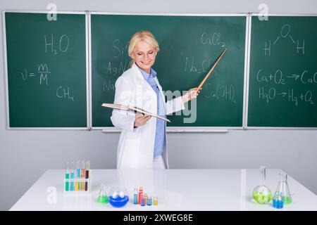 Foto einer entzückenden, cleveren Universitätsdozentin in weißem Mantel erklärt Formel isoliert auf grünem Bretthintergrund Stockfoto