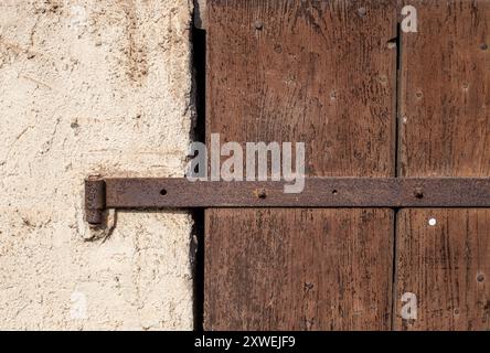 Altes Eisenscharnier am Holztor. Ländliche Architektur. Eklektisches Haus auf dem Land. Rostige Metallelemente, Konstruktionsdetails. Holztür. Stockfoto