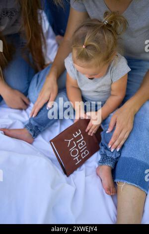 Eine Familie liest die heilige Bibel auf einem Picknick im Garten Stockfoto