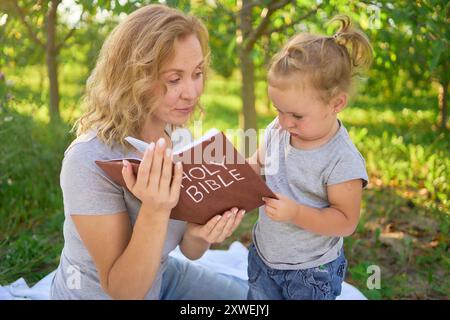 Eine Familie liest die heilige Bibel auf einem Picknick im Garten Stockfoto