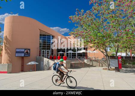 Radfahrer schlüpfen vorbei an einem modernen studentengewerkschaftsgebäude und einer Terrasse auf dem Campus der University of New Mexico – Albuquerque NM, April 2024 Stockfoto