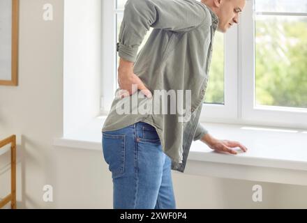 Porträt eines jungen unglücklichen Mannes mit Rückenschmerzen, der zu Hause steht Stockfoto