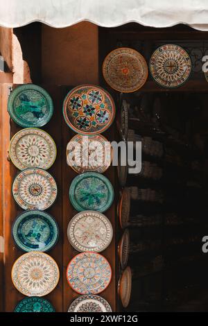 Eine Sammlung handgemalter traditioneller marokkanischer dekorativer Teller, ausgestellt in einem Ladensouk in der Medina, Marrakesch, Marokko Stockfoto