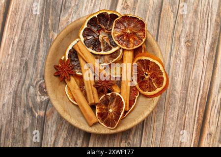 Getrocknete Orangenscheiben, Sternanis und Zimtstangen auf einem Holzteller auf einem Holztisch Stockfoto