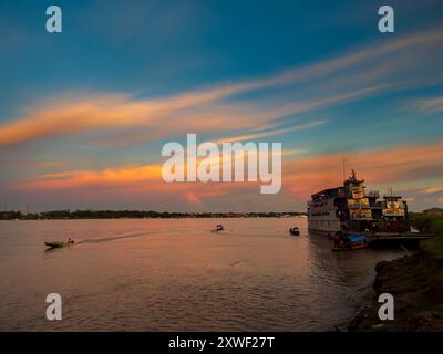 Santa Rosa, Peru - 24. März 2018: Sonnenuntergang über dem Amazonasfluss und das Frachtschiff wartet am Hafen. Amazonien, Südamerika Stockfoto