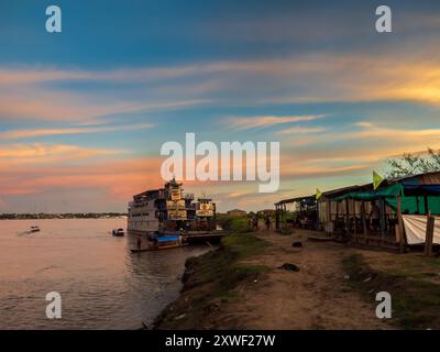 Santa Rosa, Peru - 24. März 2018: Sonnenuntergang über dem Amazonasfluss und das Frachtboot wartet am Hafen. Amazonien, Südamerika Stockfoto