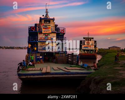 Santa Rosa, Peru - 24. März 2018: Sonnenaufgang über dem Amazonasfluss und das Frachtschiff wartet am Hafen. Amazonien, Südamerika Stockfoto
