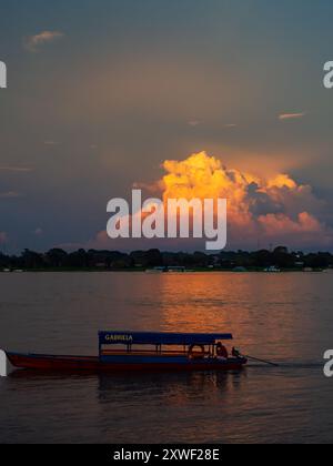 Santa Rosa, Peru - 24. März 2018: Einsames Boot im Hintergrund des Sonnenuntergangs mit wunderschönen Wolken über dem Amazonasfluss. Amazonien. Lateinamerika. Stockfoto