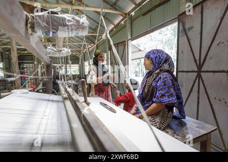 Mosammat Mahmuda Begum- Sie arbeitet seit 4 Jahren im Friendship Vocational Training Center. Sie verdient etwa 3000-4000 TK pro Monat von diesem VTC. Sie ist 32 Jahre alt. Sie musste sieben Mal nach ihrer Heirat umziehen, wegen Flusserosion und Überschwemmung. Von Freundschaft erhalten wir Schulungen und verdienen mit dieser Schulung Geld. Sie erhalten auch Hilfe bei Hochwasser mit Nahrungsmitteln und Schulungen, wie sie ihre Hygiene und Sicherheit während des Hochwassers verwalten können. Freundschaft schafft eine Verbindung zum Markt, da Freundschaft alle Tücher nimmt, die sie herstellt. Es gibt hier keine anderen Optionen, diese Kleidung zu verkaufen Stockfoto