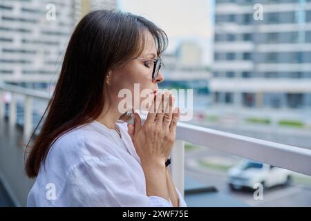 Reife ernste Frau, die Hände im Gebet hält Stockfoto