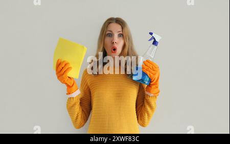 Hausreinigung, Hausfrau oder Putzfrau, schockiert überraschte Frau in Gummischutzhandschuhen mit trockenem Mikrofaserlappen und Waschmittelsprühflasche Stockfoto