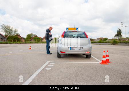 Der Schulungsleiter erklärt dem Kandidaten, wie man ein Auto besser mit Kegeln auf dem Polygon parken kann. Stockfoto