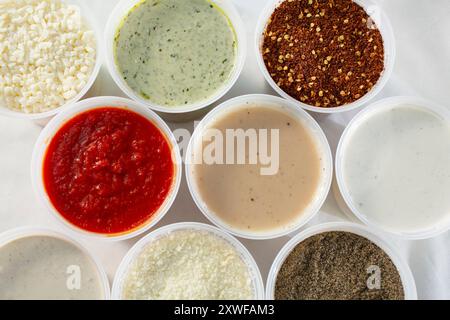 Eine Ansicht von oben nach unten auf eine Vielzahl von Soßen und Gewürzen in großen Plastikbehältern. Stockfoto