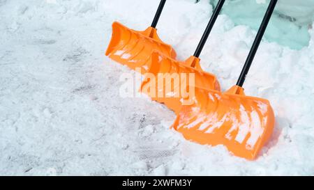 Orangefarbene Kunststoffschaufeln mit tiefem Schnee Stockfoto