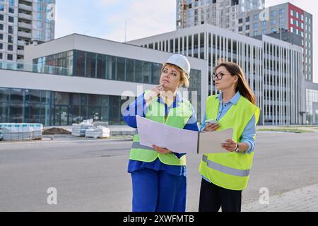 Zwei selbstbewusste Frauen, die am Bau eines Wohngebäudes arbeiten Stockfoto