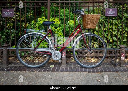 Fahrradparkplatz auf der Straße. Das Fahrrad ist an einer niedrigen Bar in einer Straße in Cambridge, Großbritannien befestigt und ignoriert keine Hinweise auf das Fahrrad. Fahrradparkplatz In Cambridge. Stockfoto