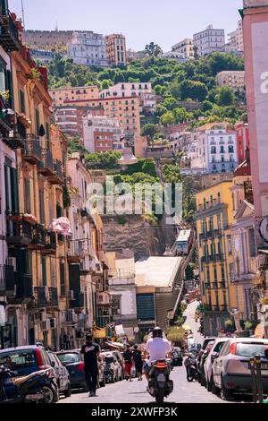 Neapel, Italien - 22. Juni 2024: Eine lebhafte Straße mit der historischen Burg Sant'Elmo, die über bunten Gebäuden am Hügel thront und die Essenszeit einfängt Stockfoto