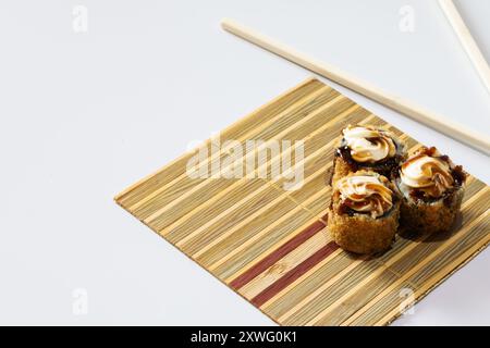 Drei heiße Brötchen mit Frischkäse und Tarasauce auf einer kleinen Matte rechts im Bild. Stockfoto