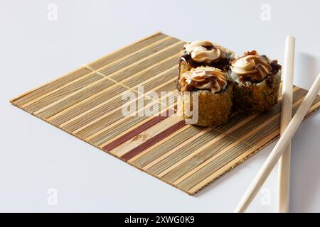 Drei heiße Brötchen mit Frischkäse und Tarasauce auf einer kleinen Bambusmatte. Stockfoto