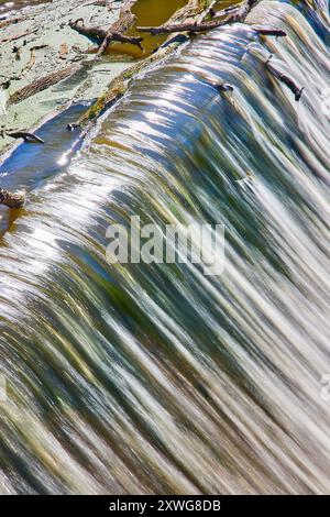 Luftaufnahme des Wasserfalls über künstlichem Weir mit Baumstämmen und Zweigen Stockfoto