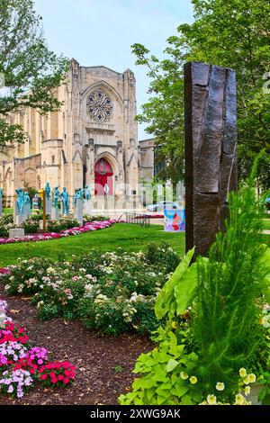 Gotische Kathedrale und moderne Skulptur im üppigen Garten mit Blick auf Augenhöhe Stockfoto