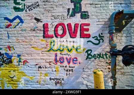 Lebendige Love Graffiti auf weißer Ziegelwand mit industriellen Elementen Stockfoto